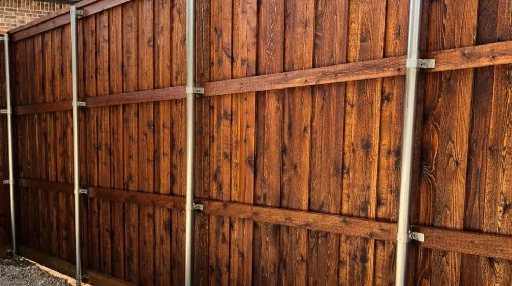 Wooden privacy fence with metal supports, showcasing rich brown stained wood texture.